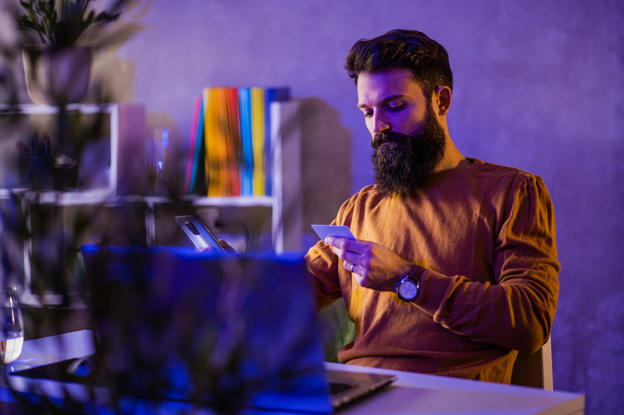 A bearded casual businessman is using his debit card and subscribing to licensed software.