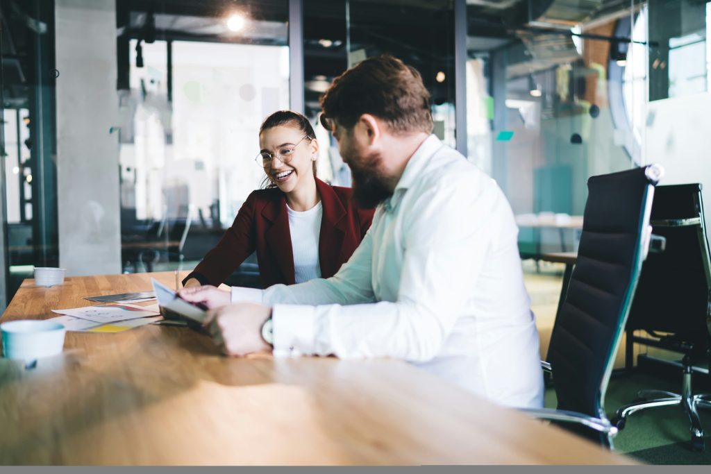 Cheerful coworker sitting at meeting room in corporation